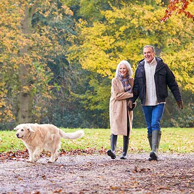 man and woman walking dog on a trail in autumn 