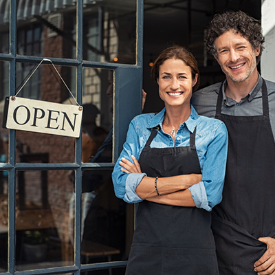 Two people in front of an open sign